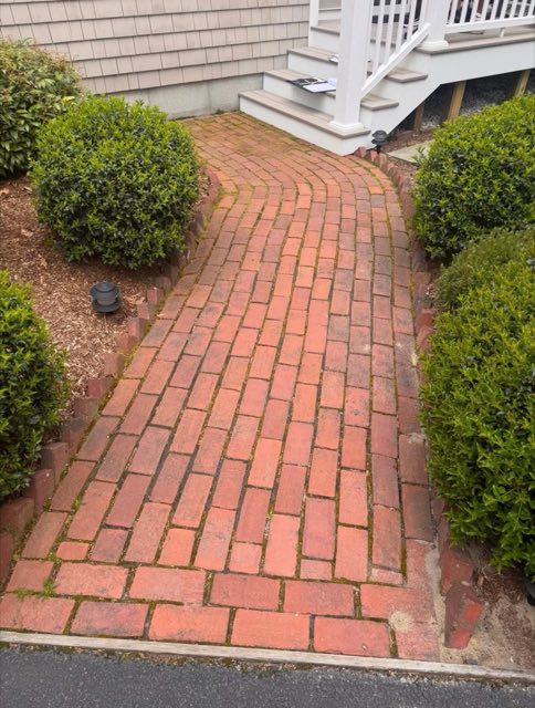 Worn red brick walkway leading to porch steps, before replacement