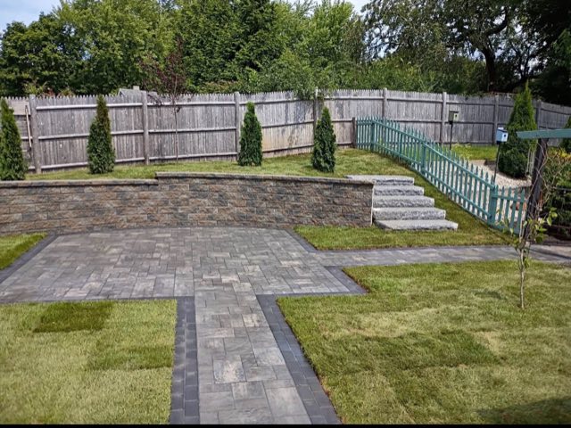 Finished paver patio and walkway with a block retaining wall and granite steps