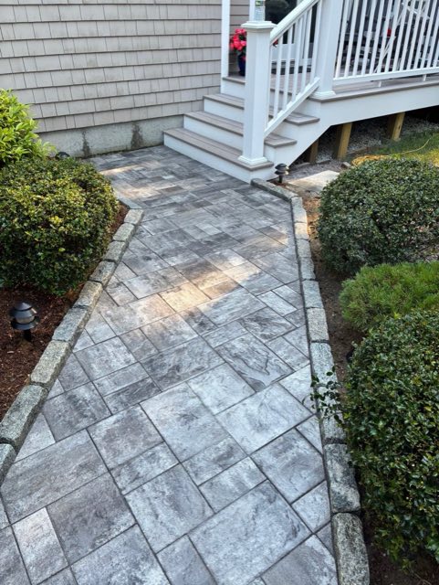 New gray paver walkway with granite edging leading to the same porch steps